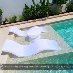 Luxury swimming pool with in-water sun loungers and landscaped surroundings in Dubai